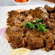 Close view of bhuna gosht served in a white plate.