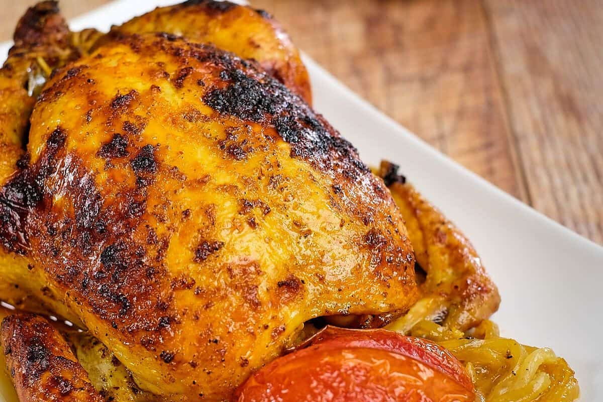 Front view of roasted saffron chicken in a white plate.