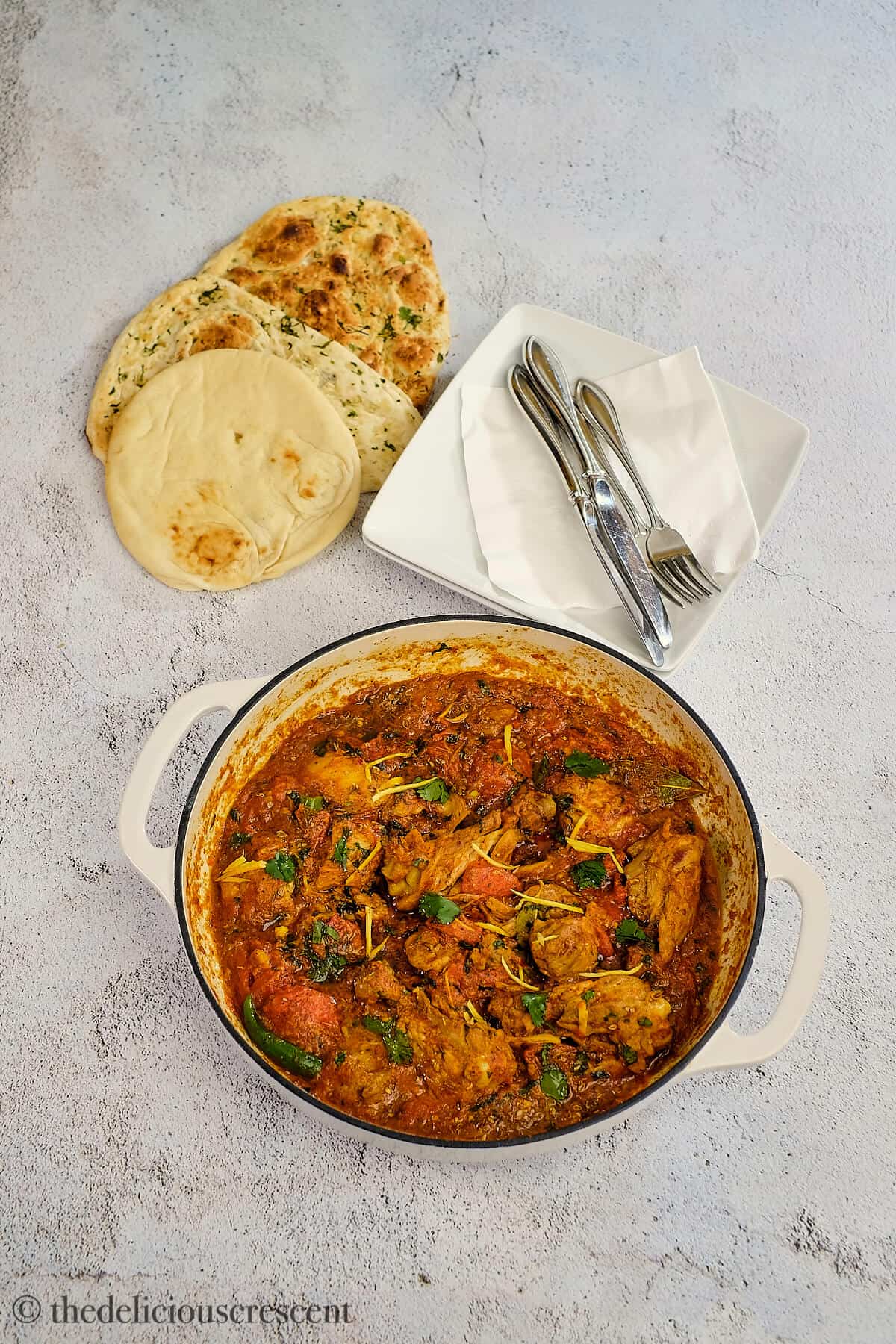 Chicken karahi served with naan on the table.