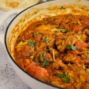Close view of kadai chicken served in a white cast iron dish.
